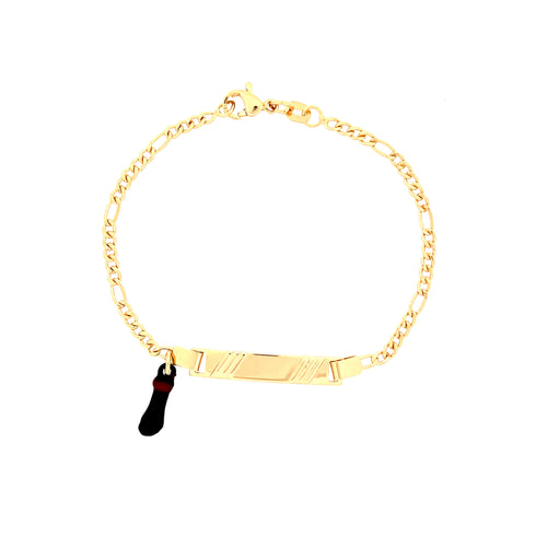 The Kids Bracelet features a Figaro link chain and a rectangular engraved plate, all crafted in 14k gold-filled material. It includes a delightful black and red Figa Hand charm, adding a whimsical touch to its elegance, making it perfect for children.
